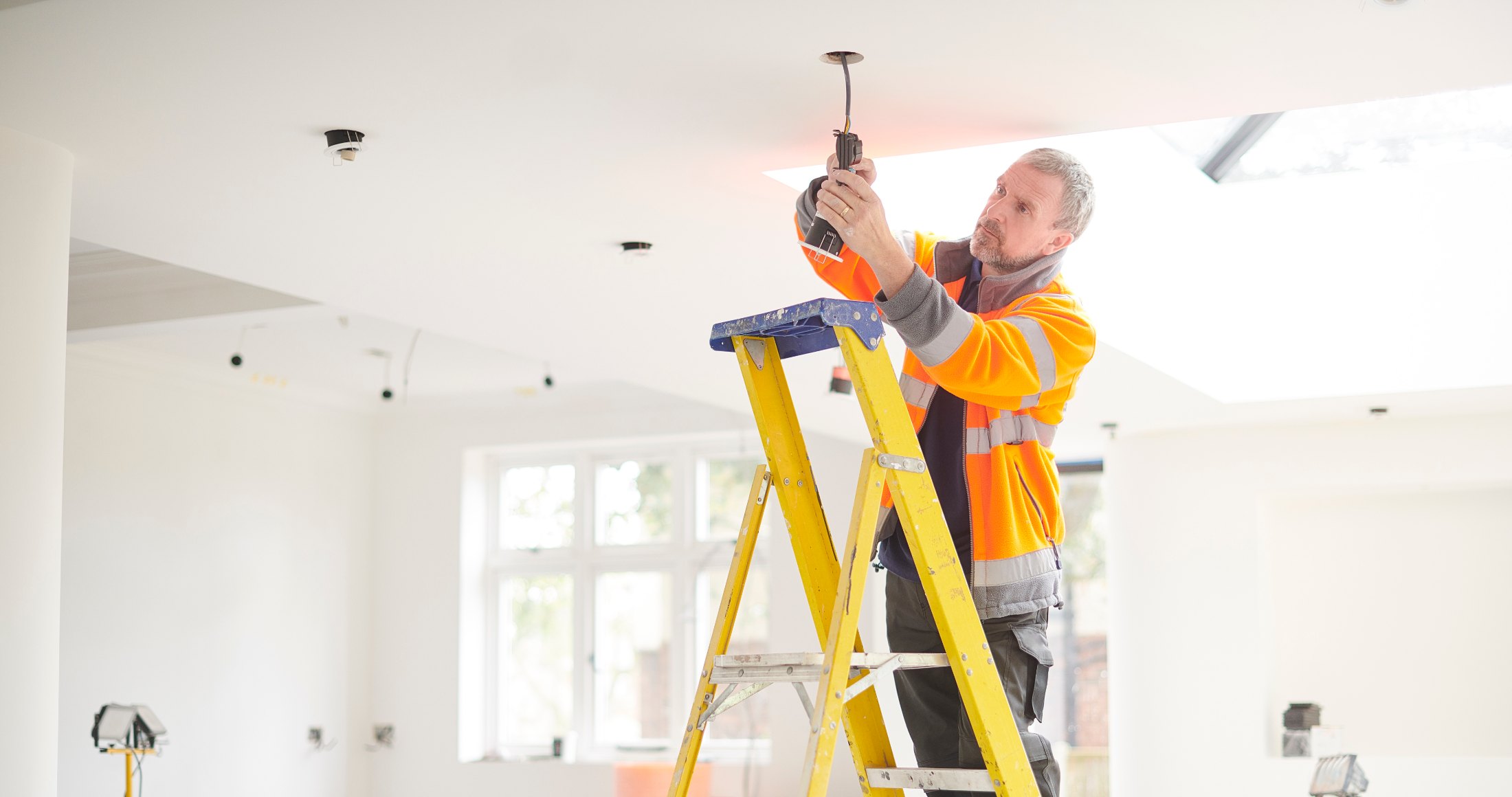 Fast Fix electrician on a stepladder repairing a ceiling light fitting