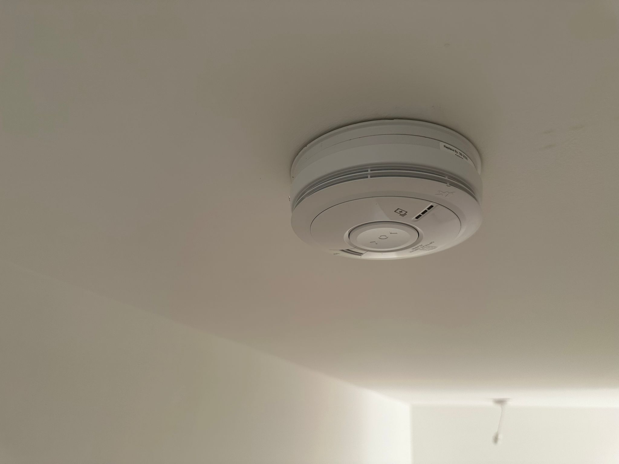 Mains-wired smoke alarm fitted to a ceiling